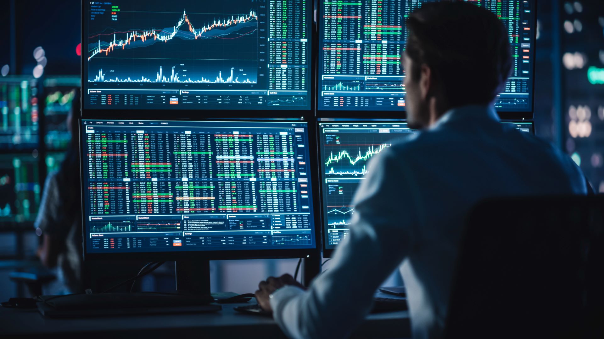 A person looking at various monitors with stock graphs on them
